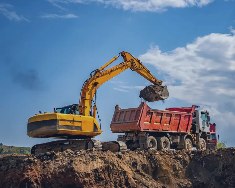 A caving machine loading dirt onto a truck at a construction site