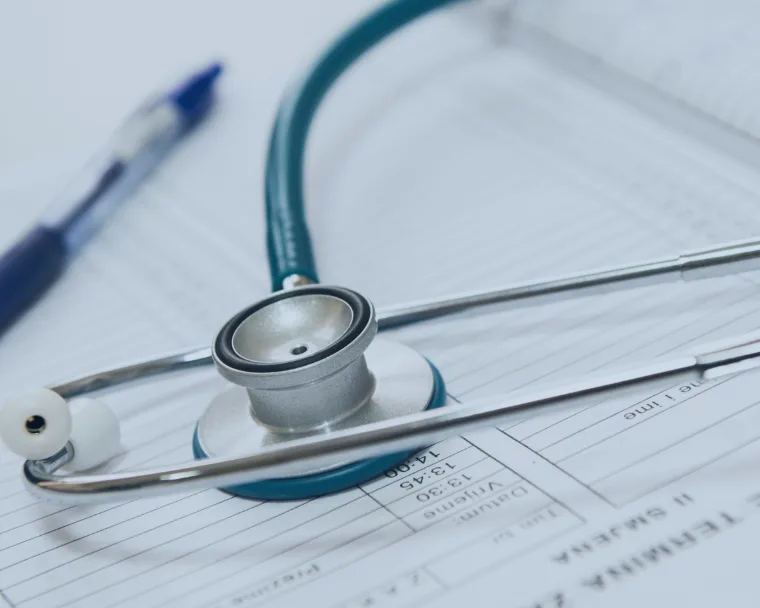 A stethoscope placed on a sheet of paper with a pen, representing the healthcare industry